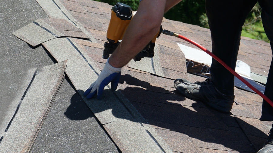 roofer with a nail gun installing an asphalt shingle roof tempe az
